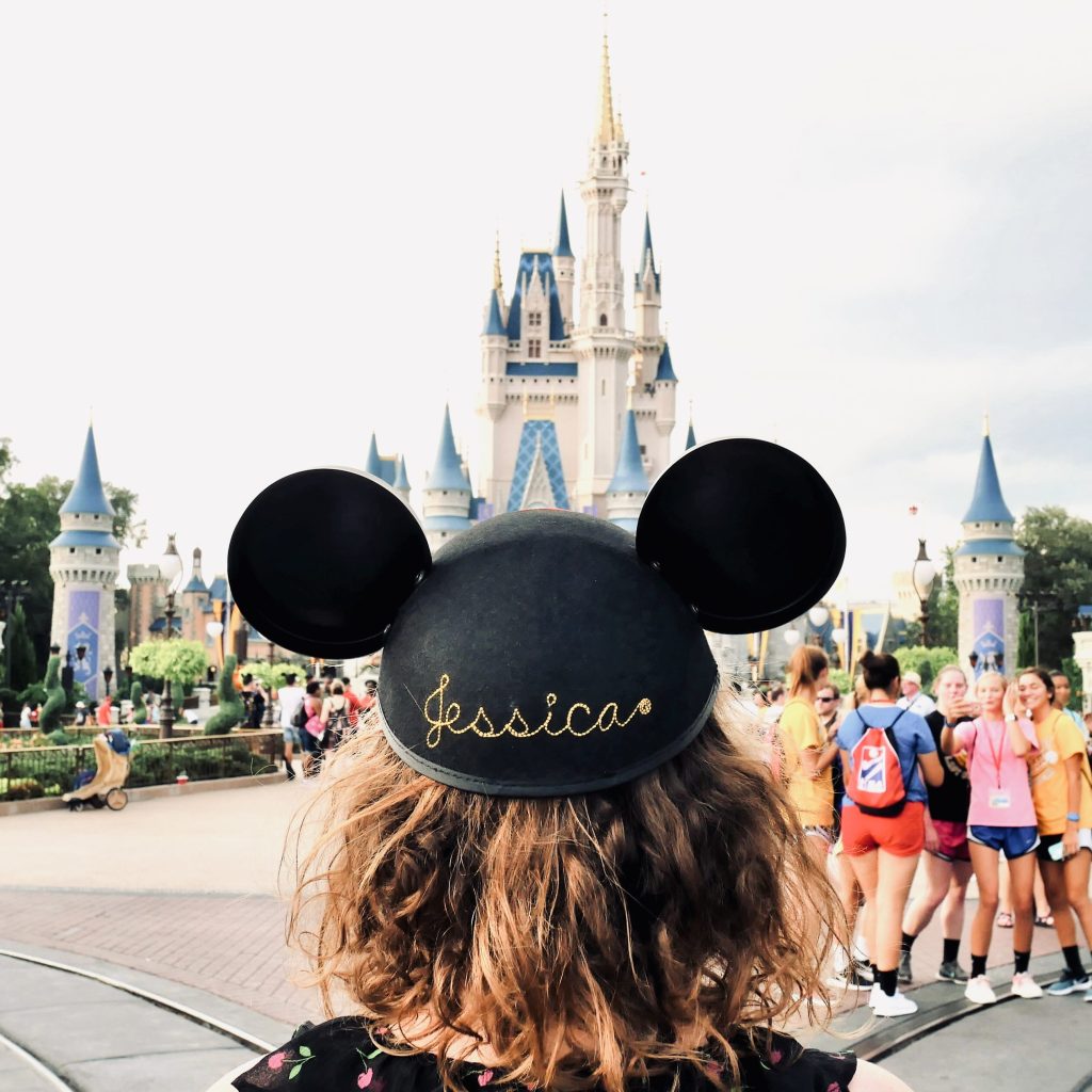 Girl with curly hair wearing Mickey Mouse ears looking at Cinderella castle at magic kingdom
