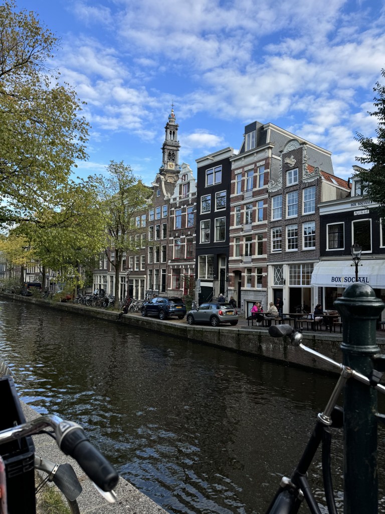 Colorful houses along a canal with bicycles and green trees in Amsterdam, The Netherlands