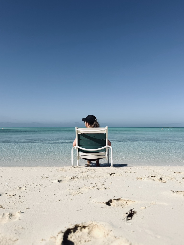 Girl sitting on beach chair looking out to ocean at castaway cay.