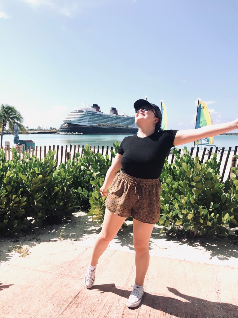 Girl looking happy at Castaway Cay with Disney Cruise Ship in the background.