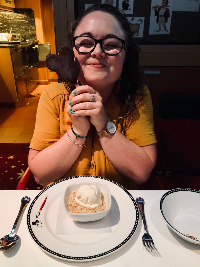 Girl smiling with Mickey-shaped ice cream bar and rice pudding dessert at animators palate on a Disney Cruise Ship.