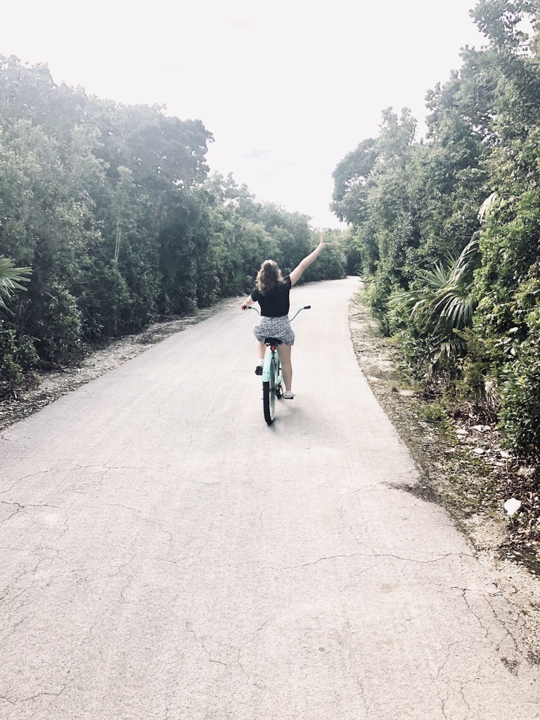 Girl riding bike on empty bike path on Castaway Cay, Bahamas