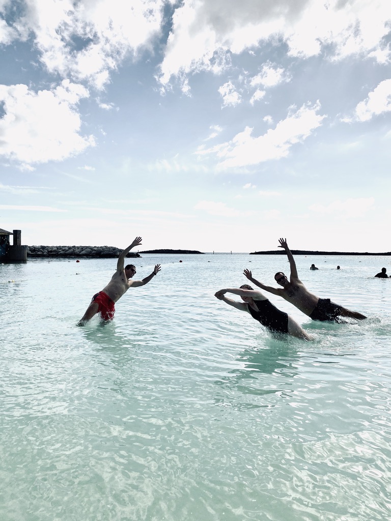 Three friends diving into water on Castaway Cay, Bahamas