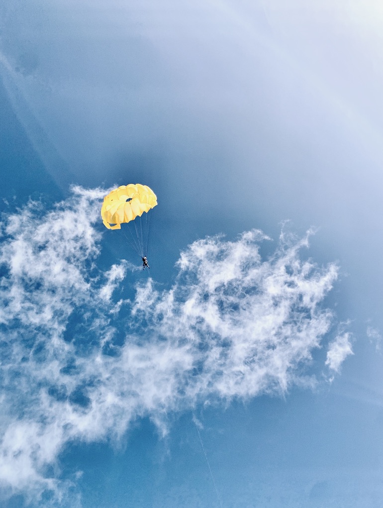 Blue skies with a yellow parasailing parachute