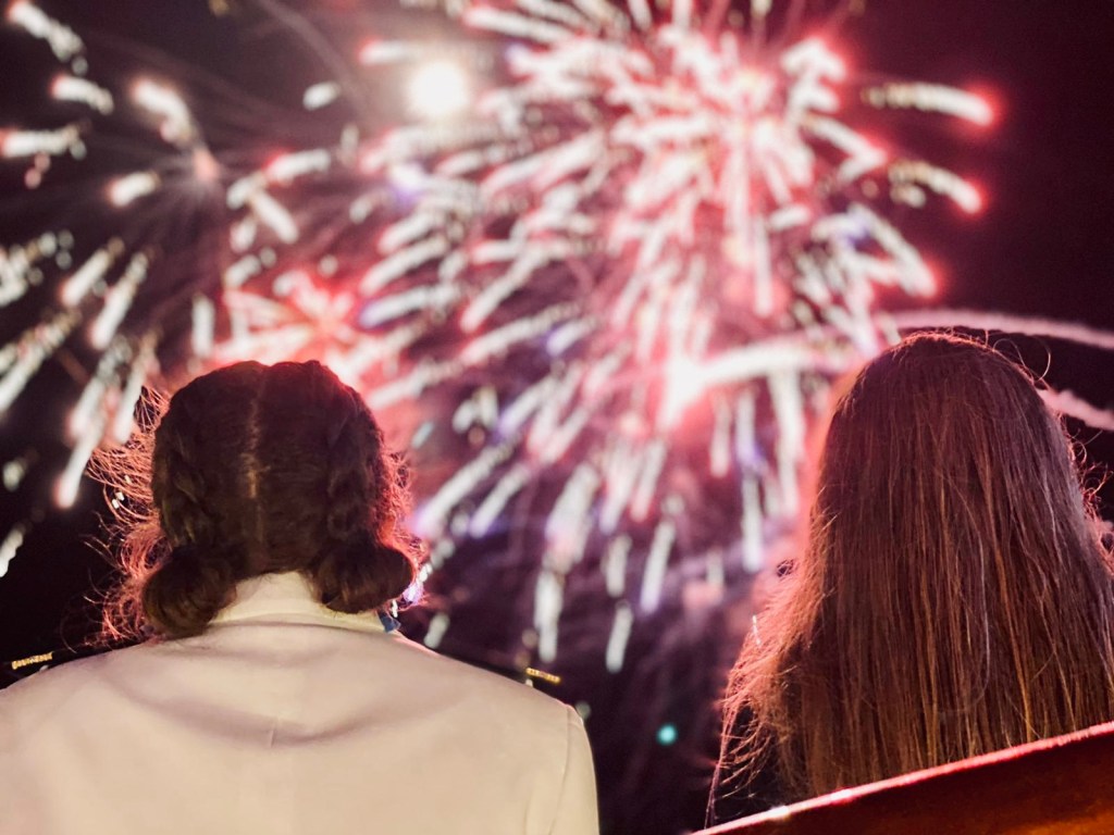 Two girls looking up at fireworks on a disney cruise ship.