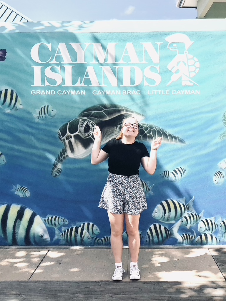 Girl smiling in front of Cayman Islands mural