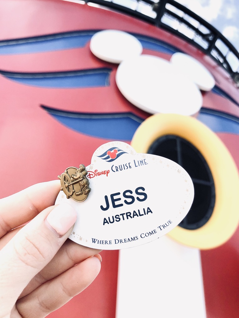 Disney Crew Member name tag with 1 year pin with Disney Cruise Line mickey funnels in the background