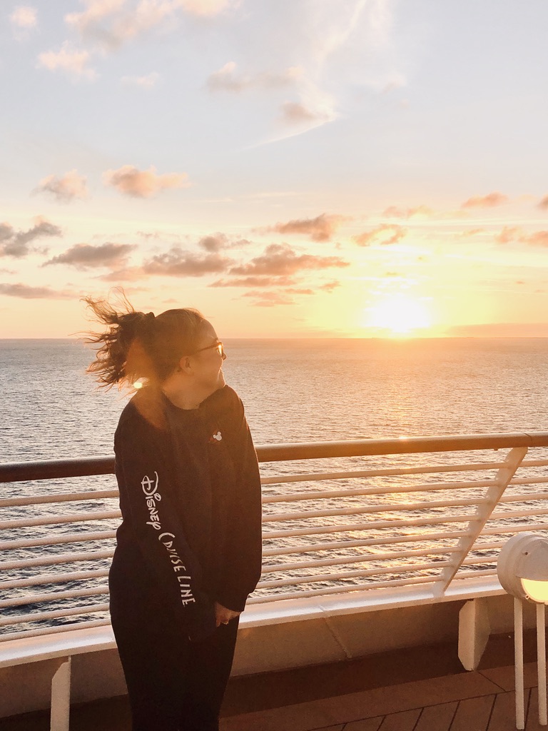 Girl looking out over ocean sunset from cruise ship deck