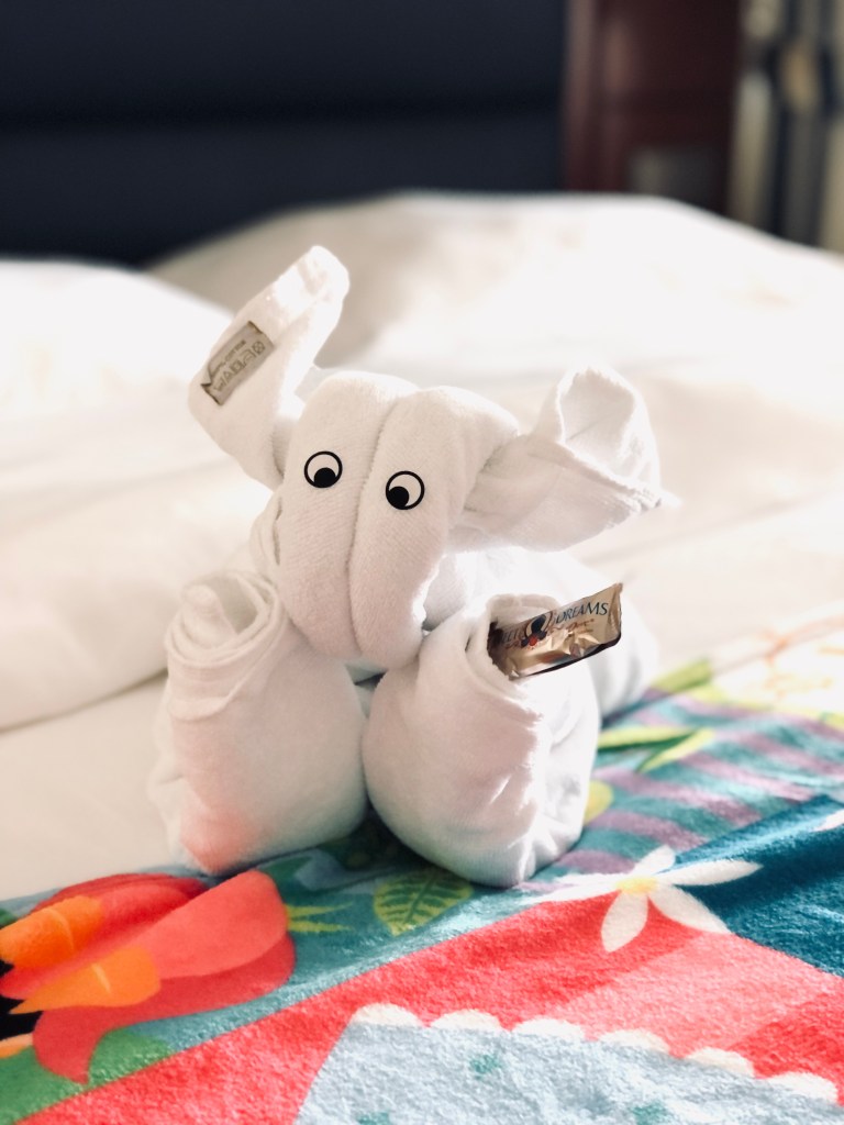 Towel animal with eyes on a bed in a stateroom onboard a disney cruise ship