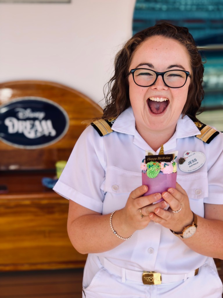 Disney cruise ship officer looking excited with a birthday cupcake onboard the Disney Dream