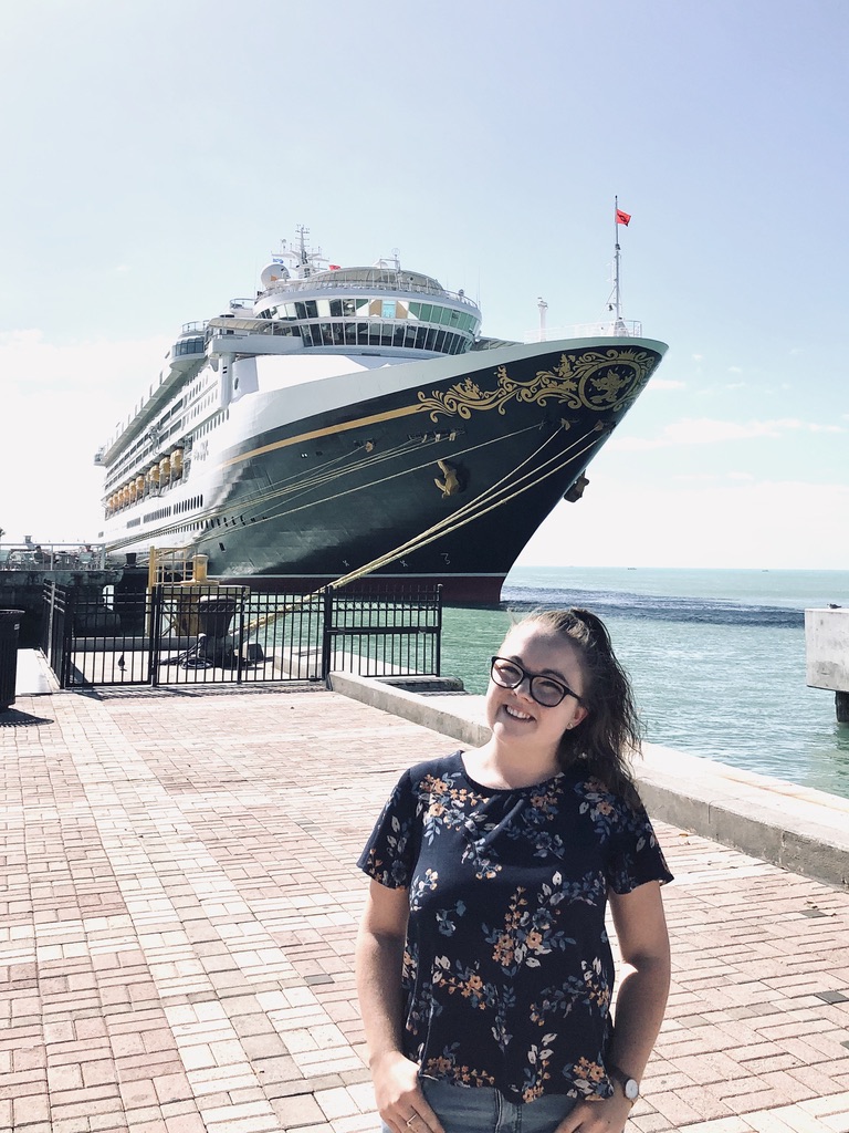 Girl smiling in front of Disney Magic cruise ship docked in Key West
