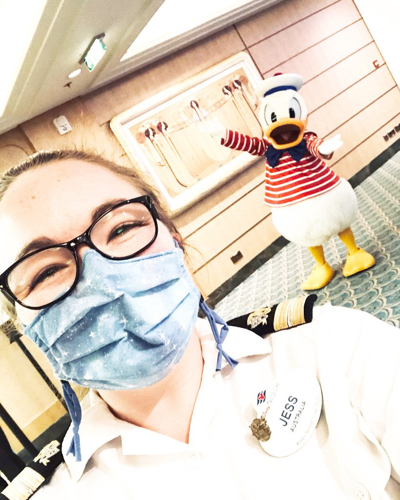 Disney Cast Member with face mask taking a selfie with Donald Duck.