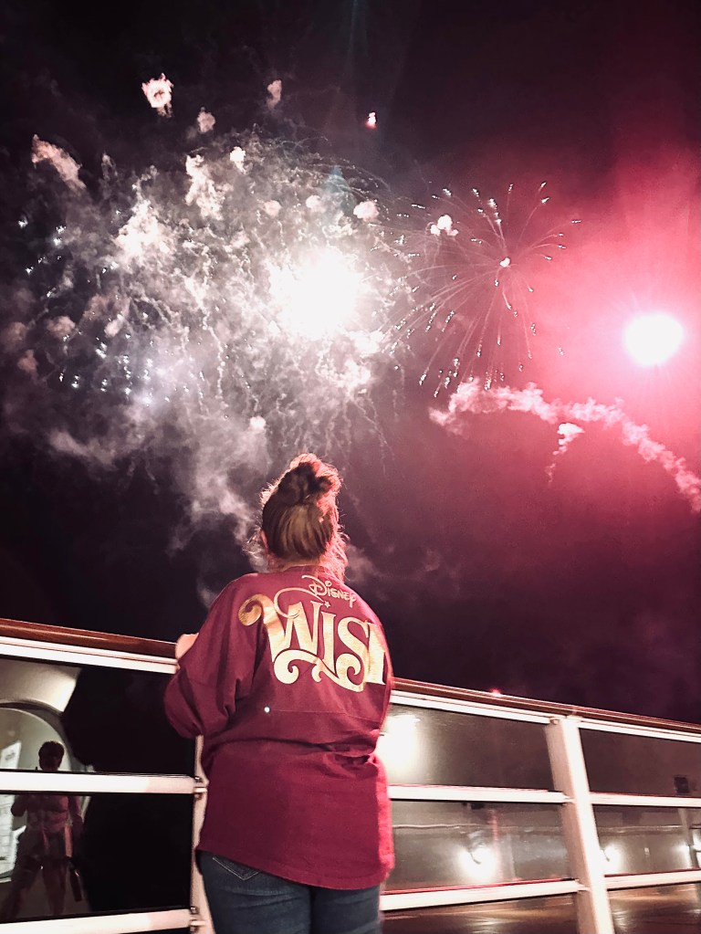Girl in Disney Wish spirit jersey looking up at fireworks on a Disney Cruise