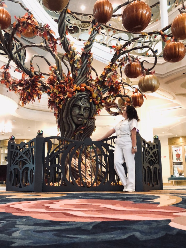 Disney Cruise Line officer standing under Halloween pumpkin tree onboard the Disney Wish