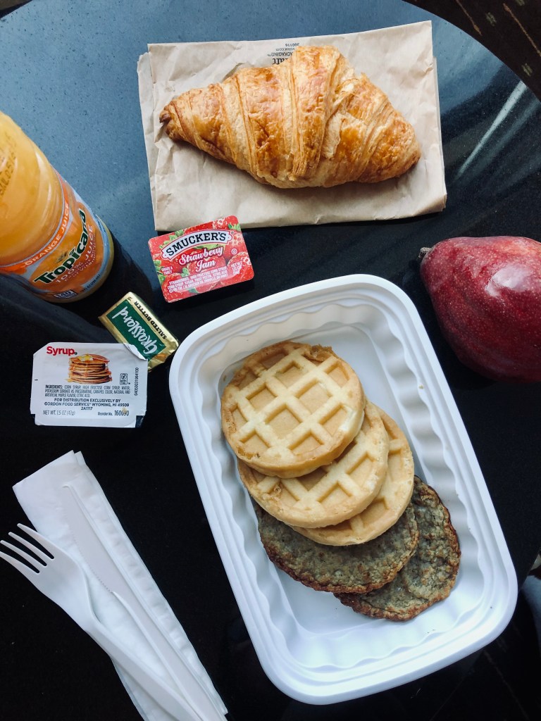 A breakfast spread including waffles, croissant and orange juice that was delivered to hotel room during quarantine.