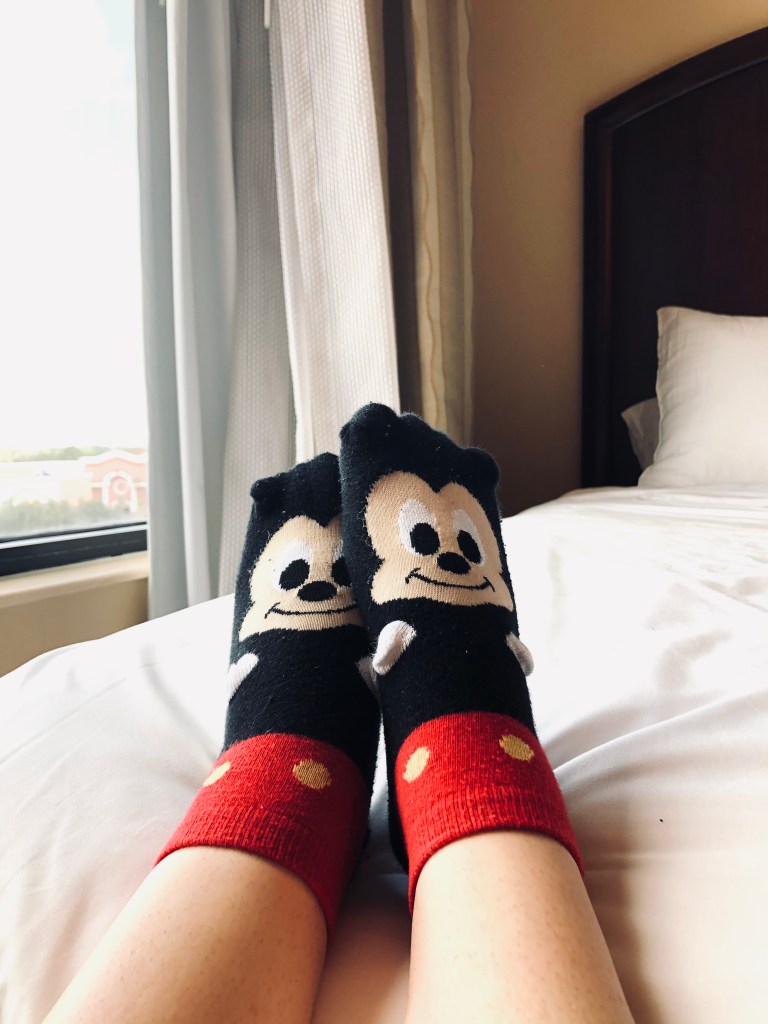 Mickey Mouse socks on bed in quarantine hotel room.
