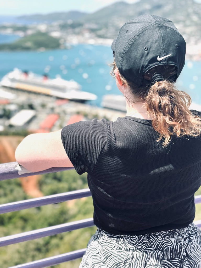 Girl wearing nike cap looking out over view of St Thomas from Paradise Point observation deck. Ocean, islands and ship in the distance.