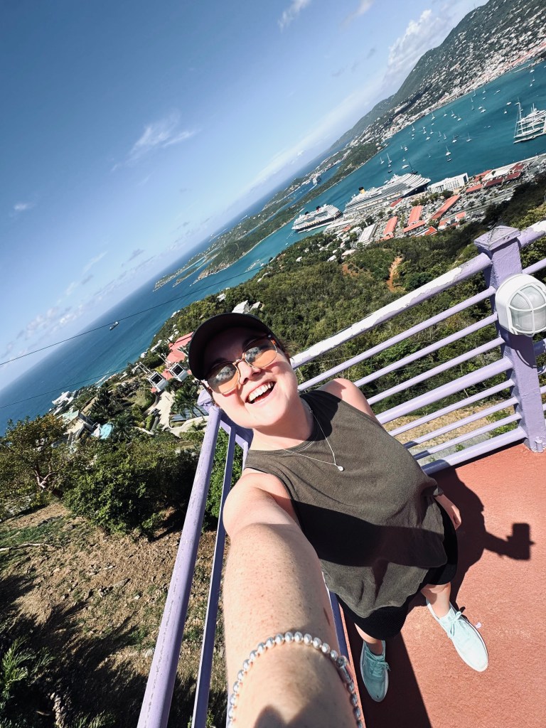 Girl taking selfie over view of St Thomas from Paradise Point observation deck. Ocean, islands and ship in the distance.