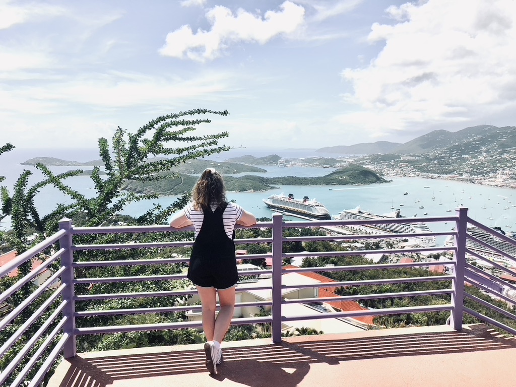 Girl looking out over view of St Thomas from Paradise Point observation deck. Ocean, islands and ship in the distance.