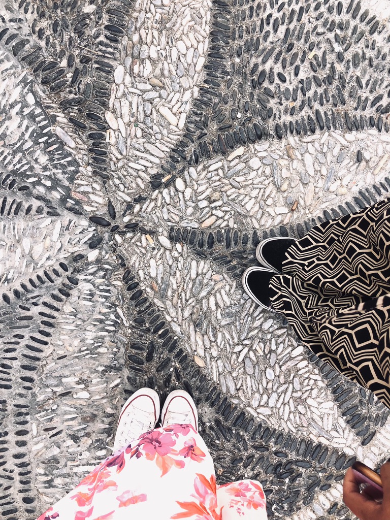 Two girls shoes on flower shaped cobble stones in Santorini, Greece