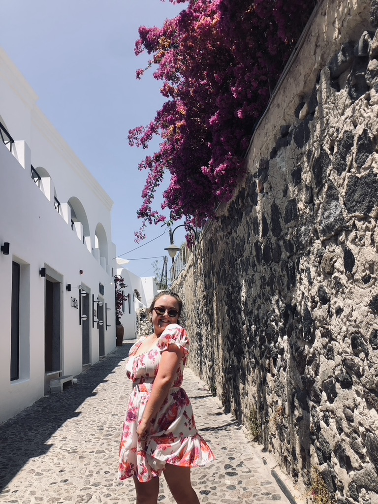 Girl in summer dress twirling on a cobble stone street in Santorini, Greece