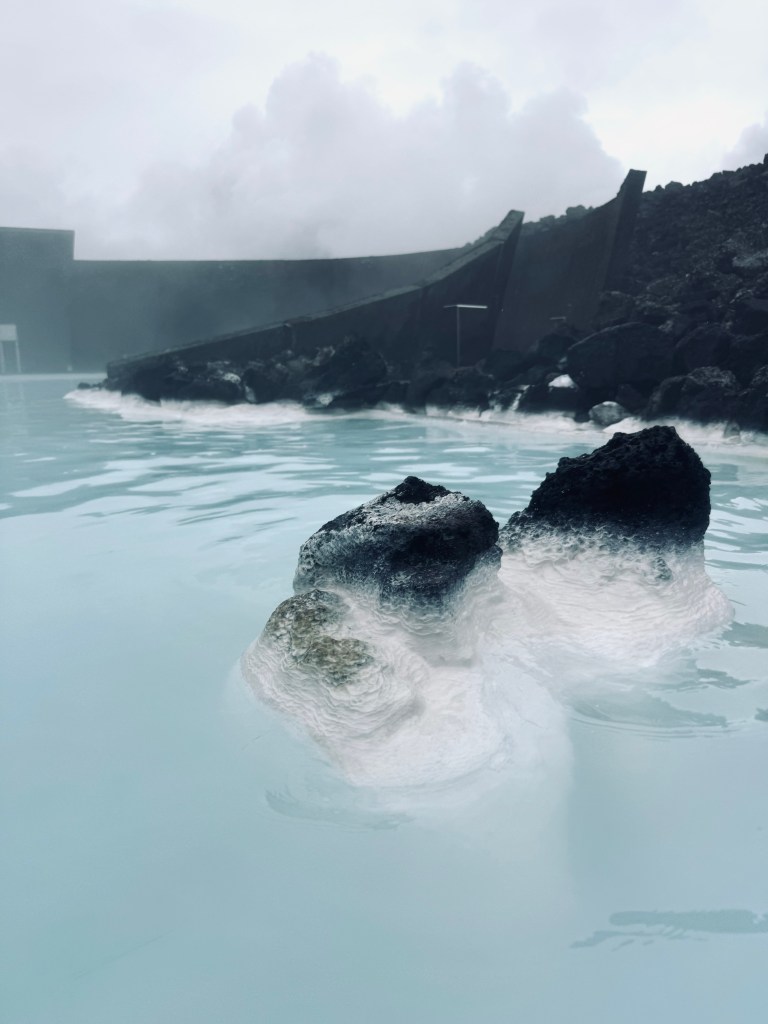 Milky blue water pools with steam and black rocks at Blue Lagoon, Iceland