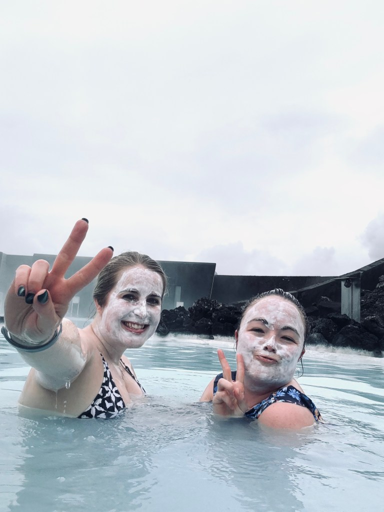 Two girls swimming in blue water with mud masks at Blue Lagoon, Iceland