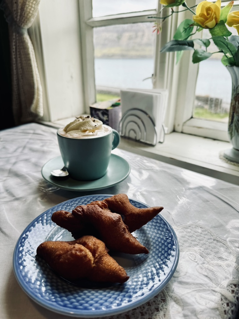 Icelandic kleina donuts and hot chocolate in a mug on a table with an old fashioned window in the Westfjords of Iceland