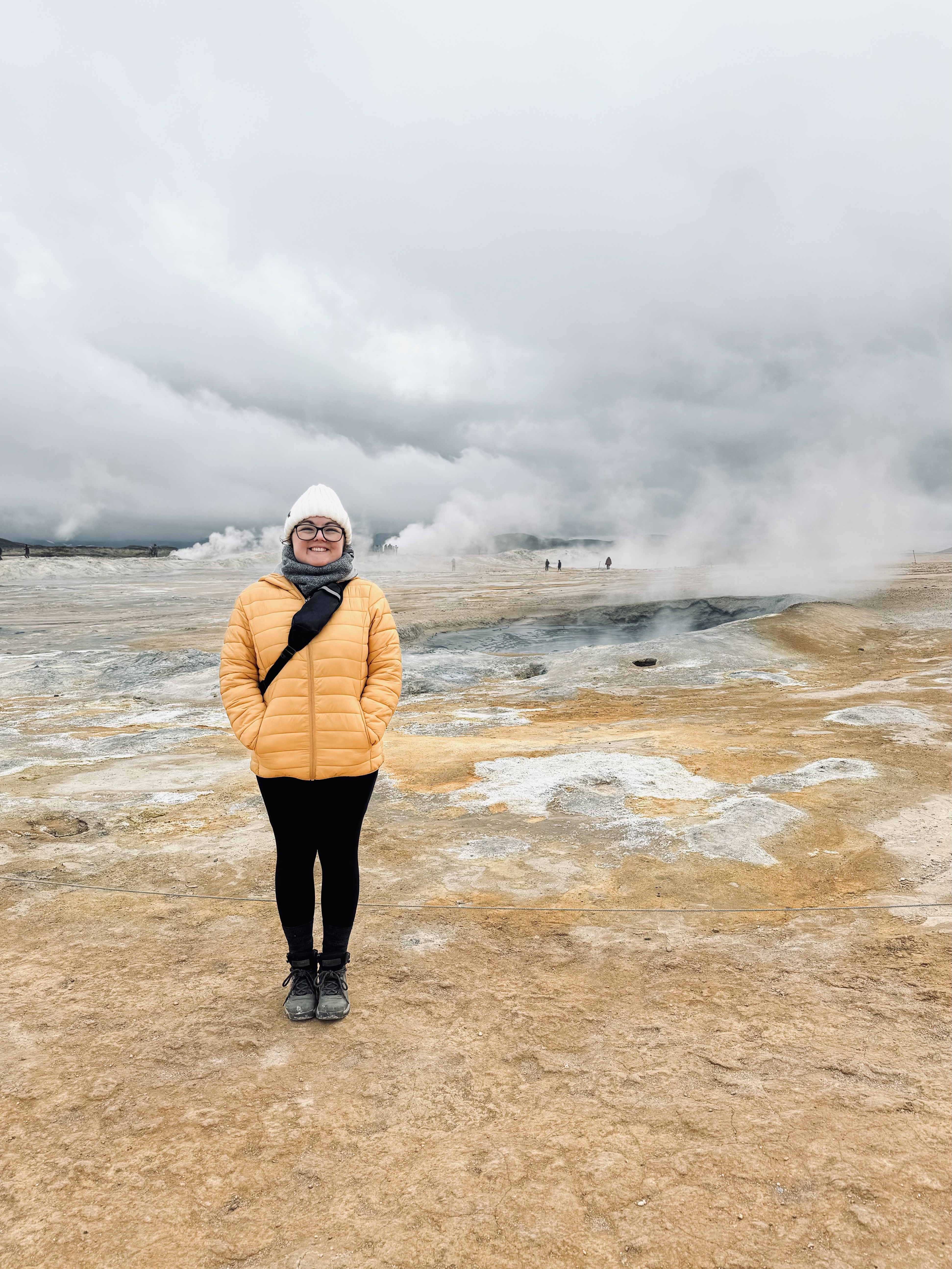 Girl in yellow coat smiling at Hverir geothermal area around Mytavn, Iceland