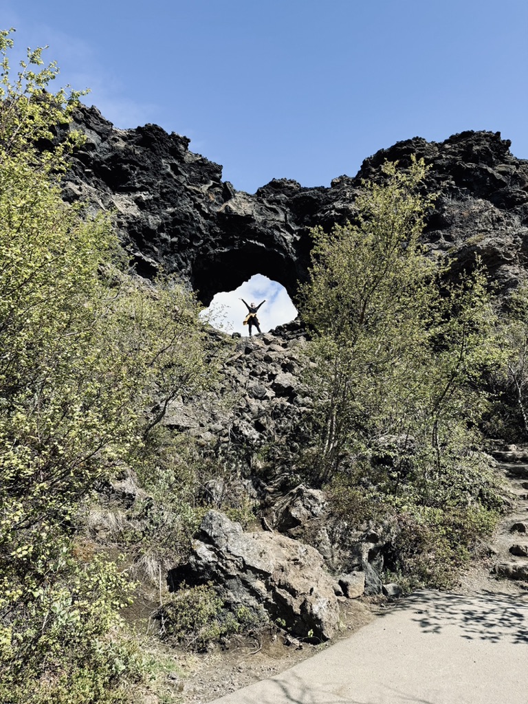 Girl in yellow coat climbing lava rocks around Mytavn, Iceland