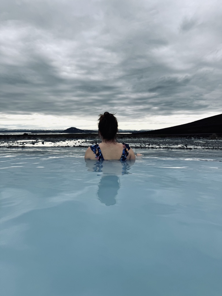 Girl bathing in Mytavn Nature baths with sunset view in Iceland
