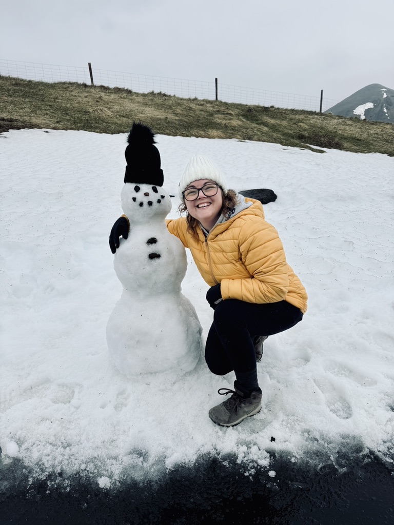 Girl in yellow coat smiling with a snowman in Mytavn, Iceland