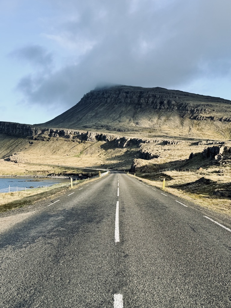 Unusual mountain formations in the distance of a straight empty road in Iceland