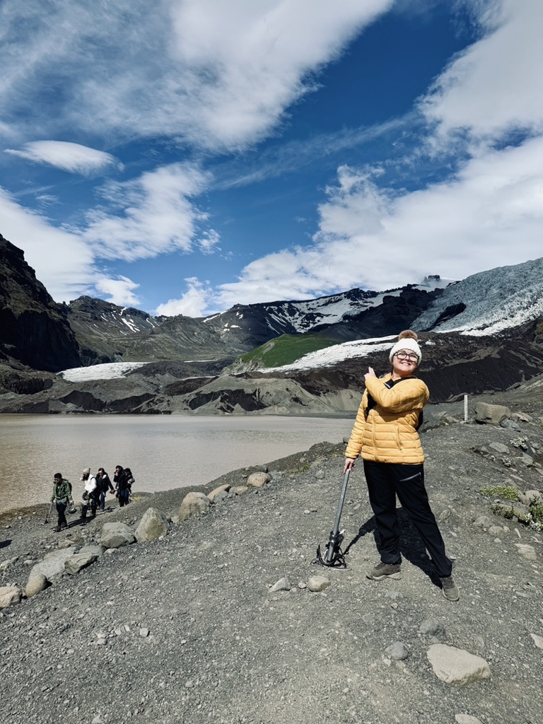 Girl in yellow coat at bottom of glacier at Skaftafell Glacier, Iceland