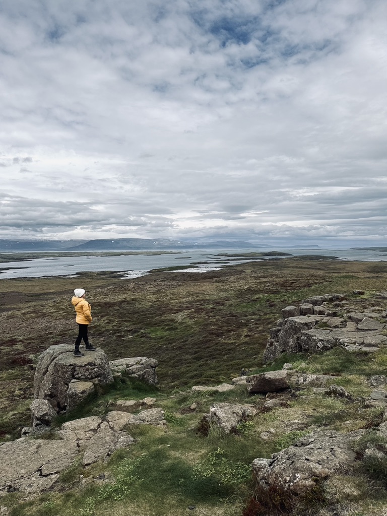 Girl in yellow coat looking out at view of Westfjords, Iceland