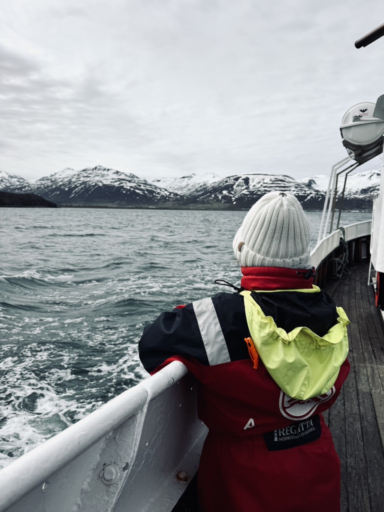 Girl in immersion suit looking for whales on whale watching boat outside of Akureyri, Iceland