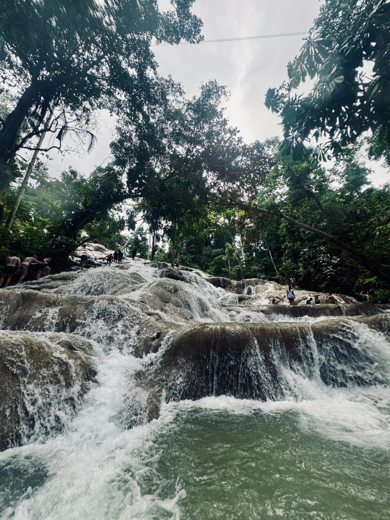 Waterfall flowing over cascading rocks with jungle background at Dunns River Falls in Jamaica
