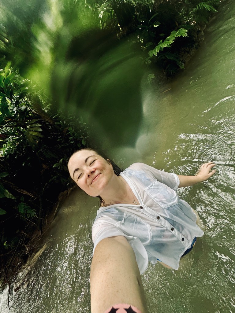 Girl taking selfie looking content while swimming in green colored water at Dunns River Falls Jamaica