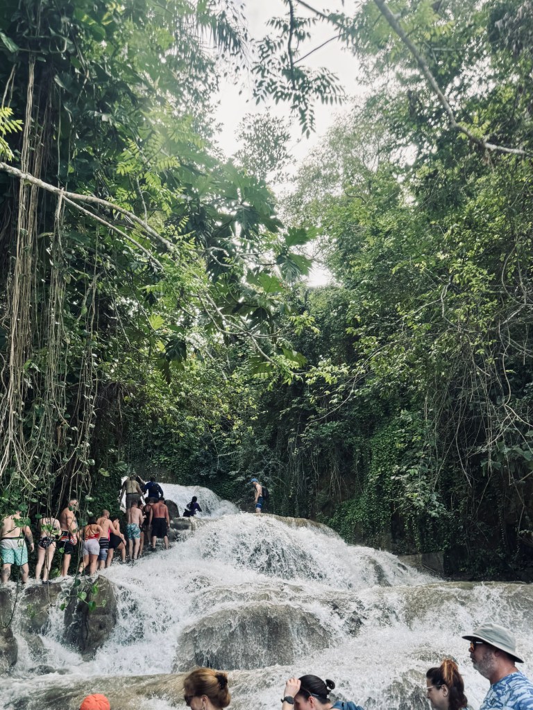 People climbing up waterfall rocks at Dunns River Falls in Jamaica