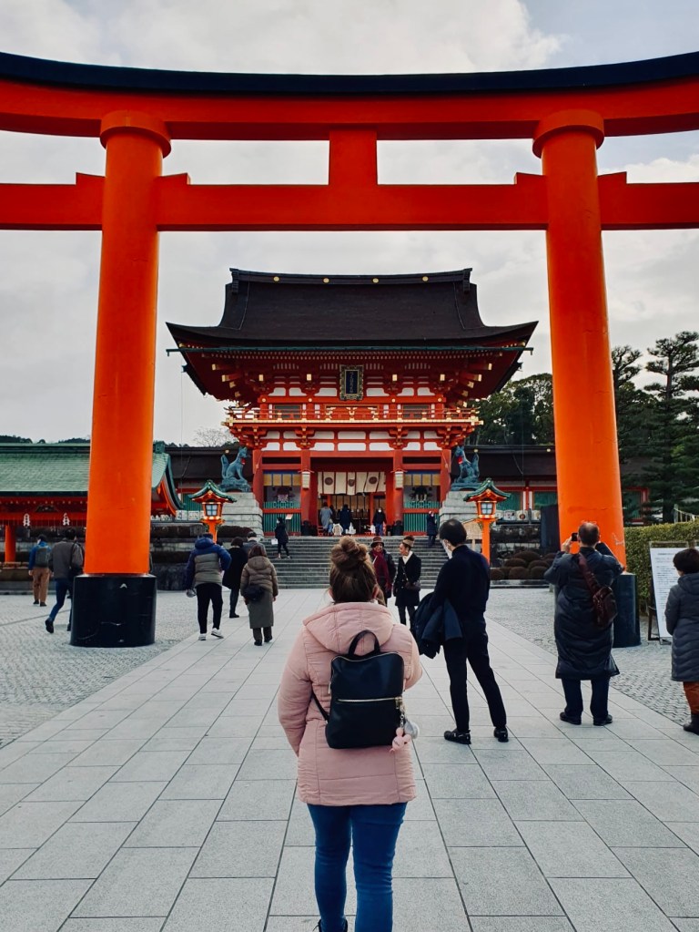 Girl walking towards entrance to Fushimi Inari shrine in Kyoto.