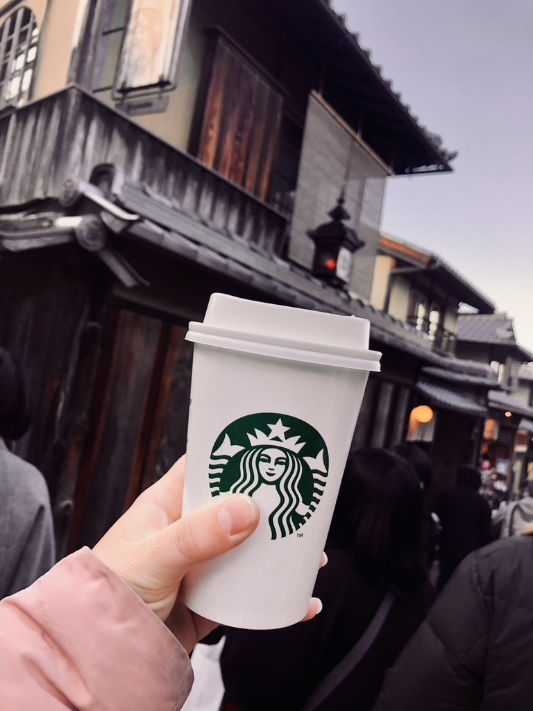 Hand holding starbucks cup in old town of Kyoto, Japan