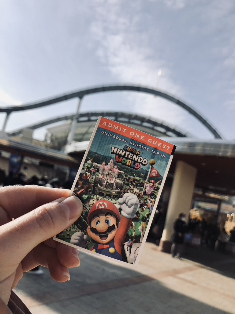 Super Nintendo World Japan ticket with rides in background.