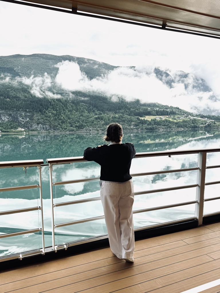 Disney Cruise Line officer looking out at view of Norwegian Fjords from deck on cruise ship