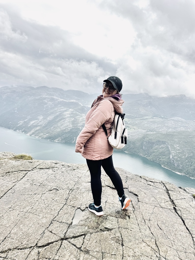 Girl posing on top of the hike with view of fjords from the top of Pulpit Rock, Norway