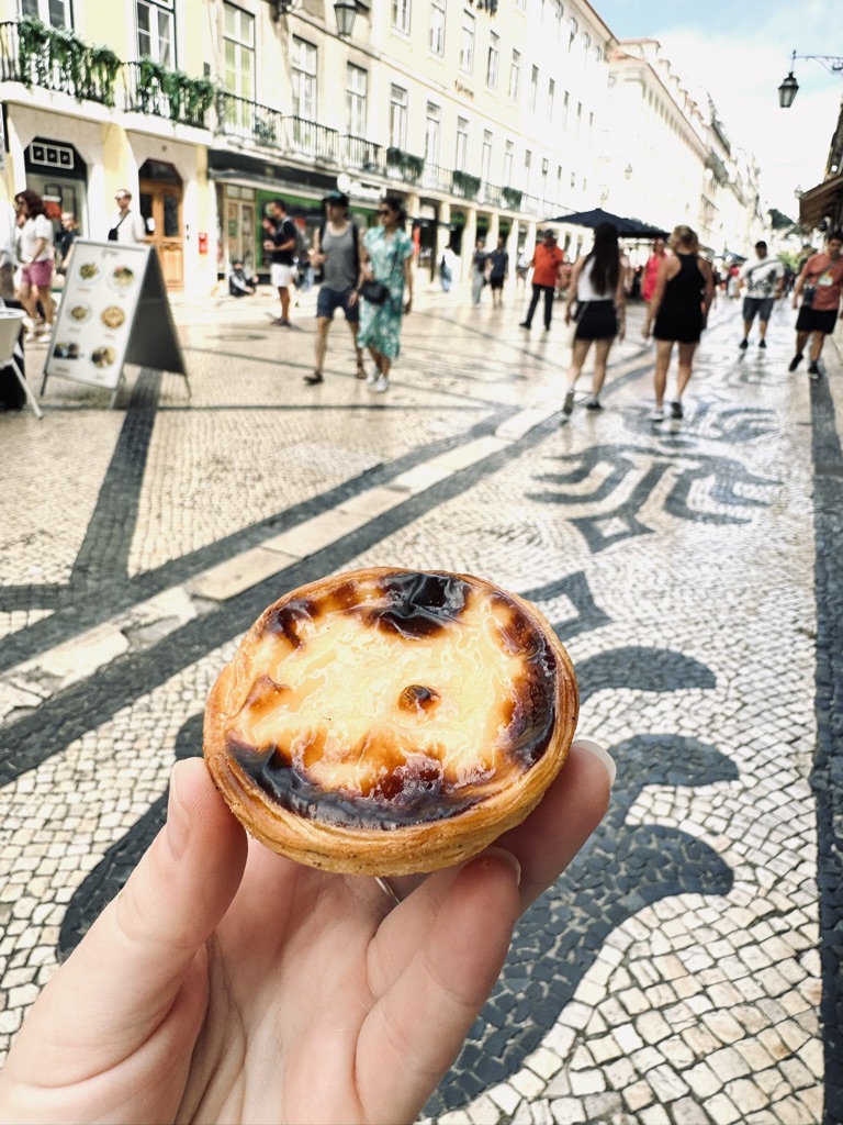 Hand holding a Pastel de Nata pastry in Lisbon, Portugal