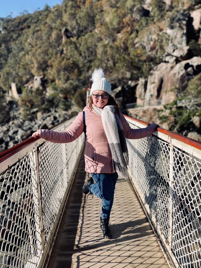 Girl in pink jacket walking on suspension bridge at Cateract Gorge in Launceston, Tasmania