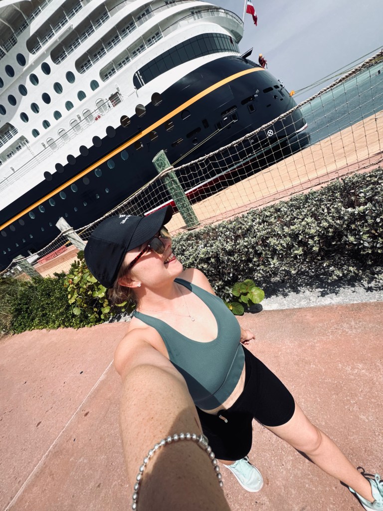Girl in gym wear running on Castaway Cay with disney cruise ship in background