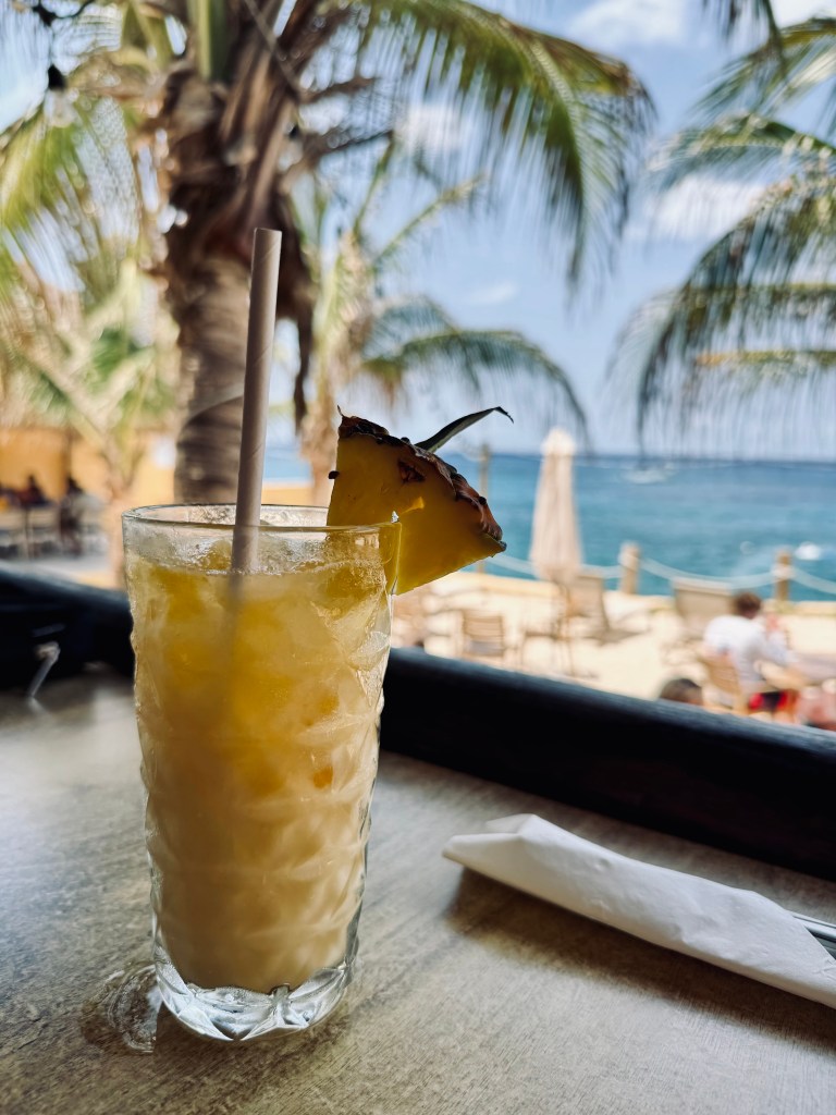 Pina Colada in a glass on a table with view of ocean in background at Jeanie's restaurant in Cozumel, Mexico