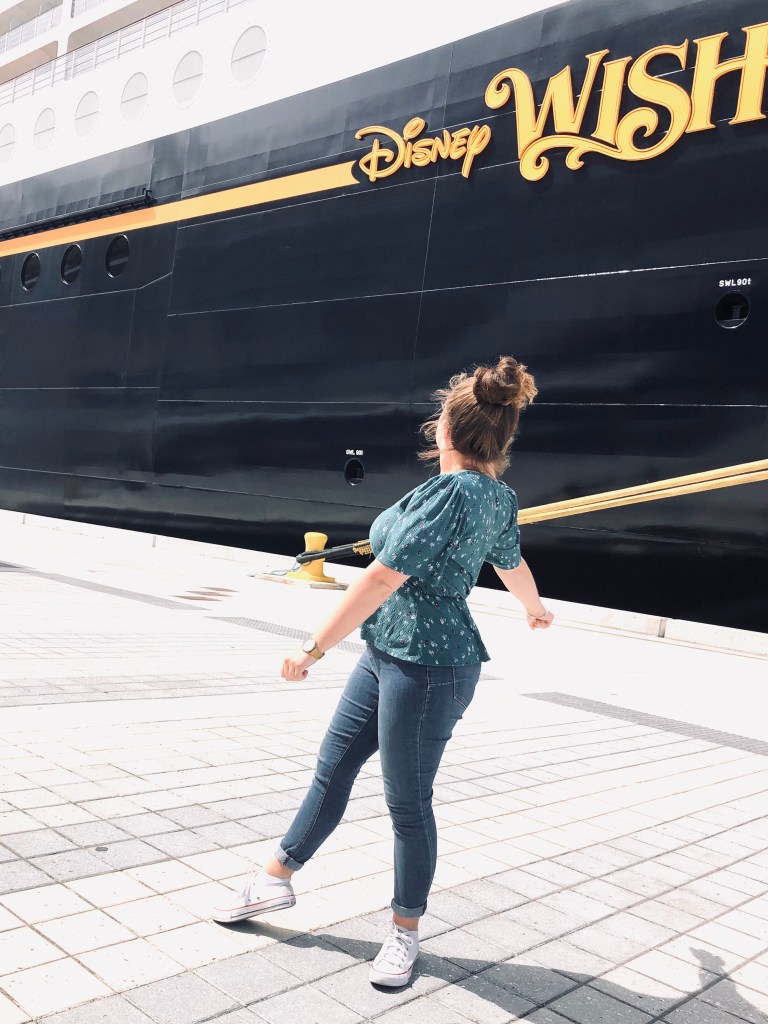 Disney Cruise ship with girl posing in front of Disney Wish logo