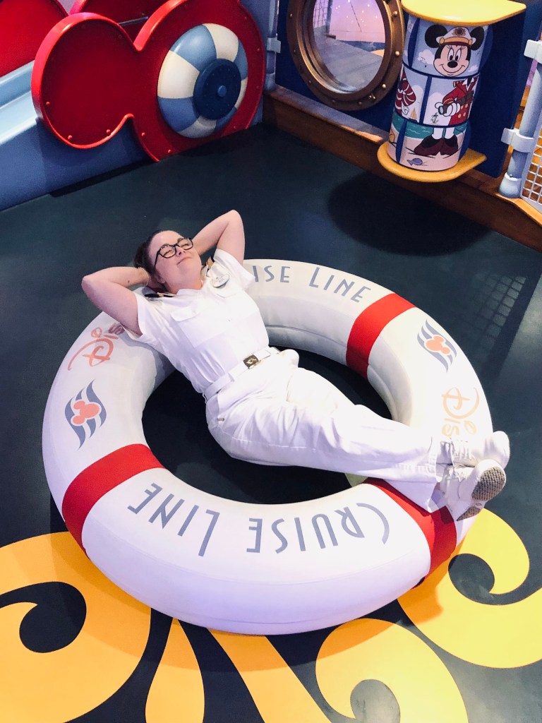 Disney Cruise Line officer relaxing on a giant life ring in the kids club onboard a Disney Cruise ship